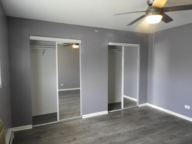 13715 S Stewart Ave Unit 2E, Riverdale, IL 60827 - unfurnished bedroom featuring wood finished floors, baseboards, two closets, and a ceiling fan