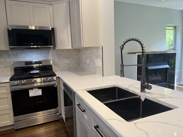 1333 N Burling St Unit B, Chicago, IL 60610 - kitchen featuring appliances with stainless steel finishes, a sink, light stone counters, backsplash, and dark wood-type flooring