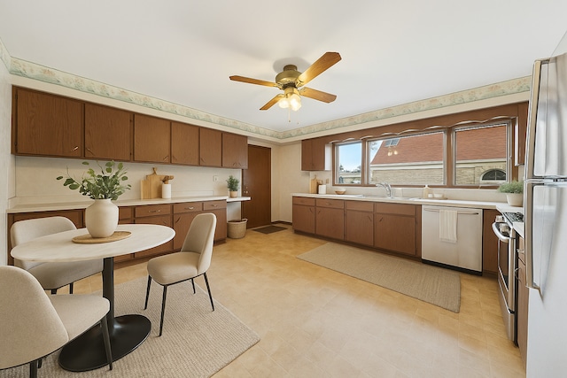 kitchen featuring brown cabinets, appliances with stainless steel finishes, light countertops, a ceiling fan, and light floors