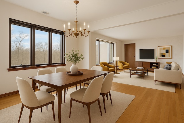 dining area with a chandelier, baseboards, visible vents, and light wood-style floors