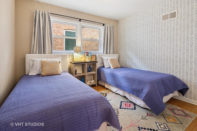 3762 N Odell Ave, Chicago, IL 60634 - bedroom featuring wallpapered walls, visible vents, wood finished floors, and an accent wall