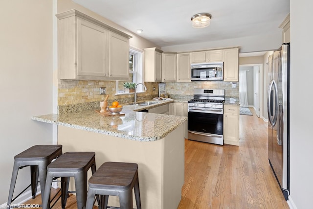 3762 N Odell Ave, Chicago, IL 60634 - kitchen featuring light stone countertops, appliances with stainless steel finishes, a sink, a peninsula, and decorative backsplash