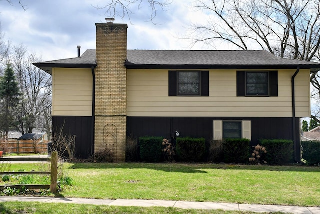 view of front of home featuring fence, a chimney, and a front yard