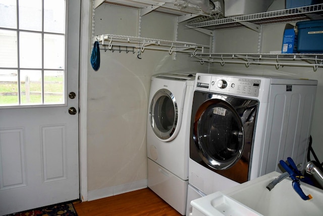 washroom with baseboards, wood finished floors, independent washer and dryer, and laundry area