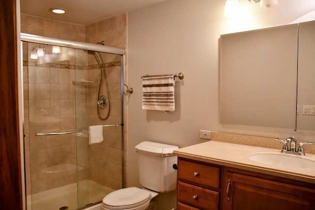 bathroom with toilet, vanity, and a stall shower
