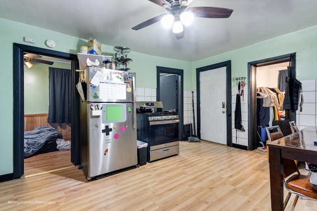 3041 S Drake Ave, Chicago, IL 60623 - kitchen with light wood-style flooring, stainless steel appliances, a ceiling fan, and wainscoting