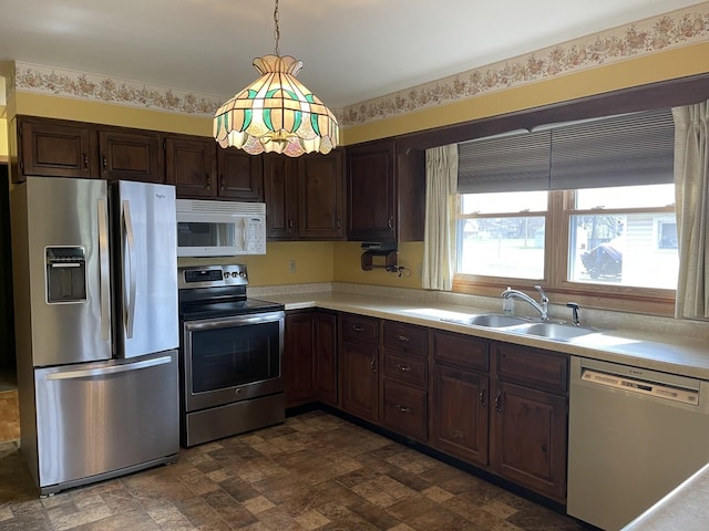 kitchen featuring light countertops, stone finish flooring, a sink, appliances with stainless steel finishes, and dark brown cabinets