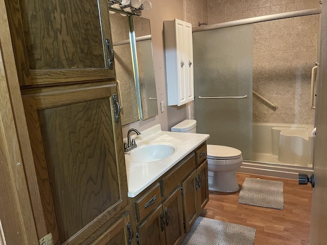 bathroom featuring toilet, a stall shower, vanity, and wood finished floors