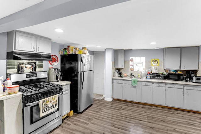 kitchen with light countertops, light wood-style floors, under cabinet range hood, and appliances with stainless steel finishes