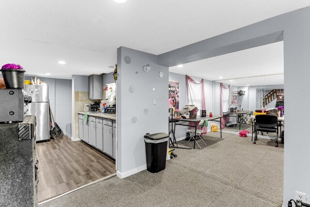 kitchen featuring a textured ceiling, baseboards, recessed lighting, gray cabinetry, and freestanding refrigerator
