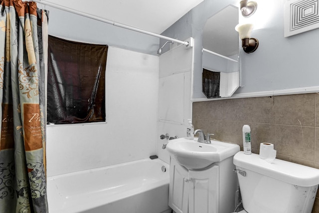 bathroom featuring tile walls, toilet, shower / tub combo with curtain, and vanity