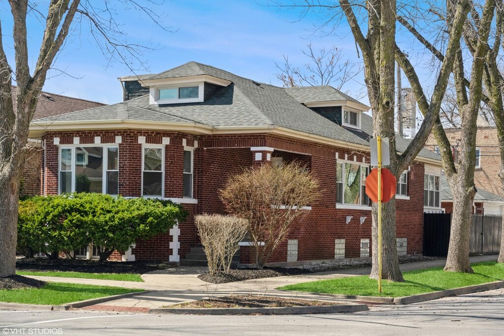8200 S Paxton Ave, Chicago, IL 60617 - view of front of property featuring fence, brick siding, and roof with shingles
