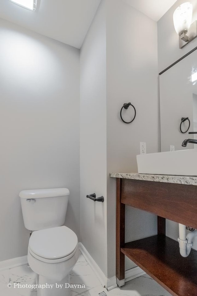 half bath featuring marble finish floor, baseboards, and toilet