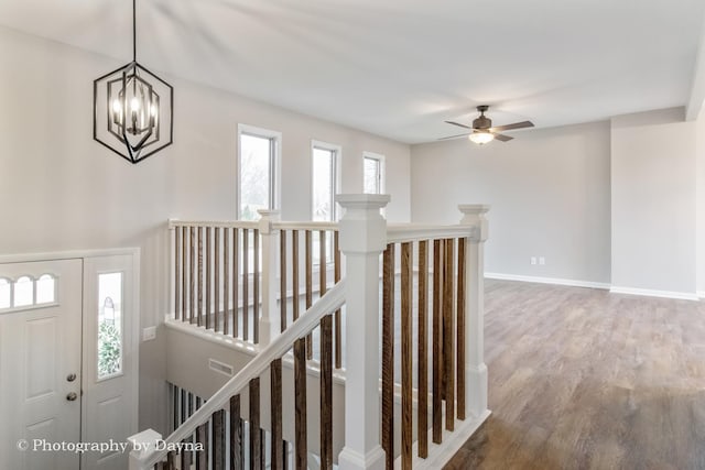 interior space featuring baseboards, visible vents, wood finished floors, and ceiling fan with notable chandelier