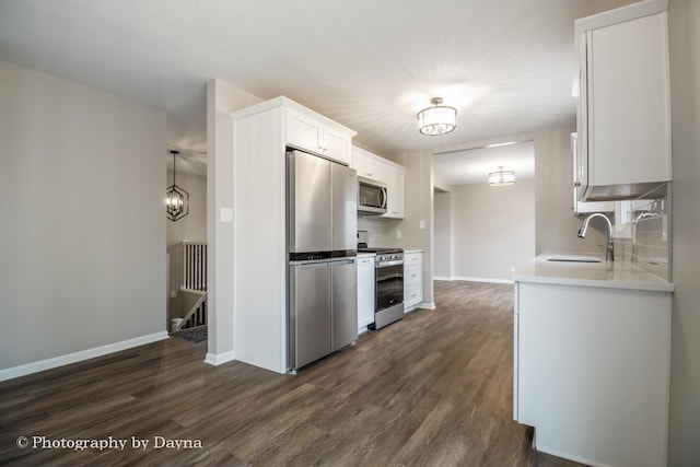 kitchen featuring decorative backsplash, dark wood-style flooring, appliances with stainless steel finishes, a sink, and an inviting chandelier
