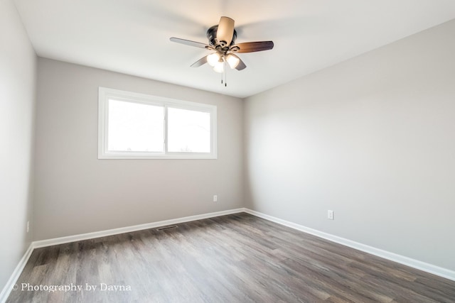 spare room with baseboards, dark wood-style flooring, and a ceiling fan