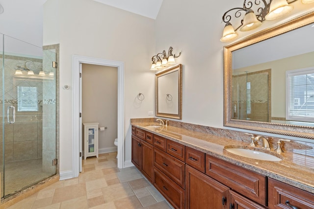 bathroom featuring double vanity, a sink, a stall shower, and toilet