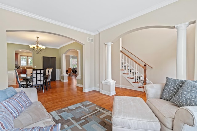 living room featuring crown molding, an inviting chandelier, arched walkways, wood finished floors, and visible vents