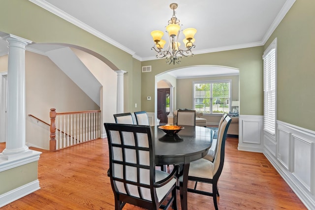 dining space with arched walkways, a chandelier, light wood-style flooring, and visible vents
