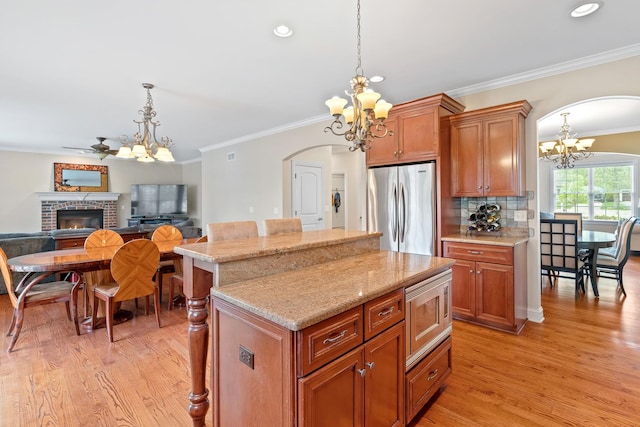 kitchen with arched walkways, appliances with stainless steel finishes, an inviting chandelier, and ornamental molding