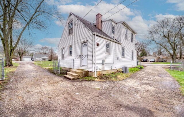 26W441 Geneva Rd, Wheaton, IL 60187 - view of property exterior featuring central air condition unit, a shingled roof, a detached garage, a chimney, and fence