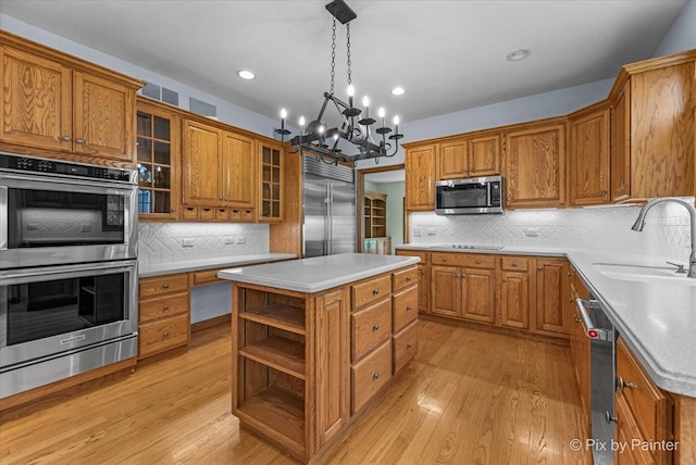 kitchen featuring a sink, tasteful backsplash, stainless steel appliances, and brown cabinets
