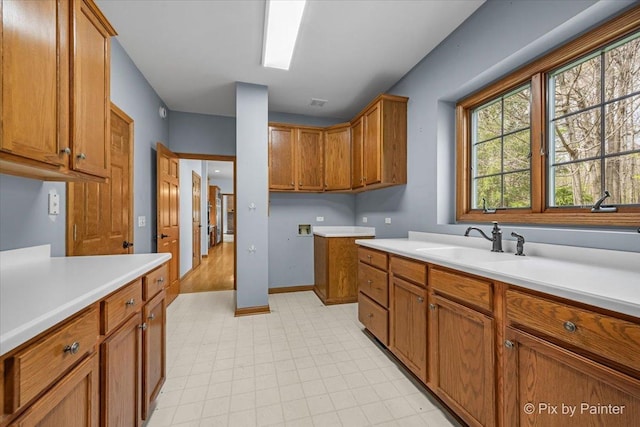 kitchen with light countertops, brown cabinetry, and a sink