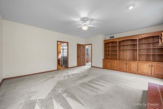 spare room featuring ceiling fan, light colored carpet, and baseboards