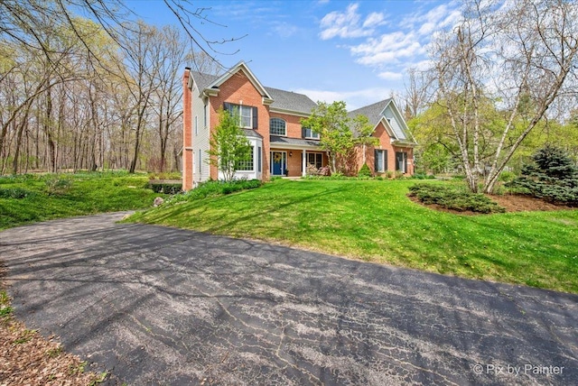 traditional-style home with a chimney, a front lawn, and brick siding