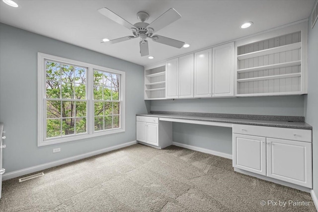 unfurnished office with ceiling fan, light carpet, built in study area, baseboards, and visible vents