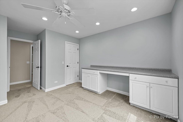 unfurnished office featuring light carpet, baseboards, built in study area, ceiling fan, and recessed lighting