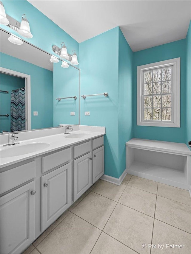 full bath featuring baseboards, double vanity, tile patterned floors, and a sink