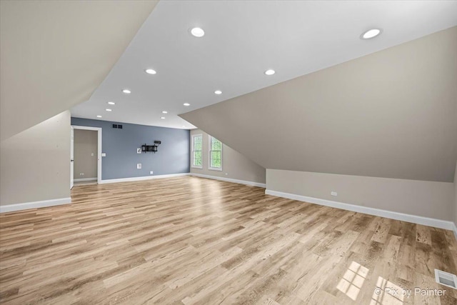 additional living space with visible vents, vaulted ceiling, baseboards, recessed lighting, and light wood-style flooring