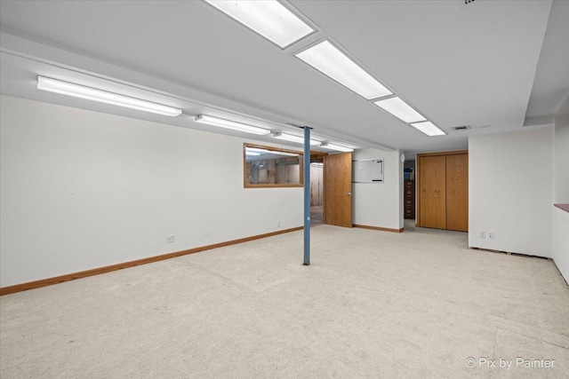 finished below grade area with baseboards, visible vents, and light carpet