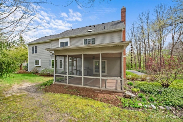 back of house featuring a sunroom, a lawn, and a chimney