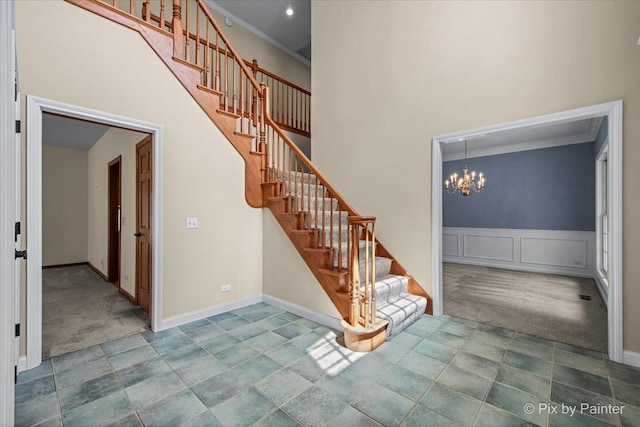 staircase with an inviting chandelier, carpet flooring, and crown molding