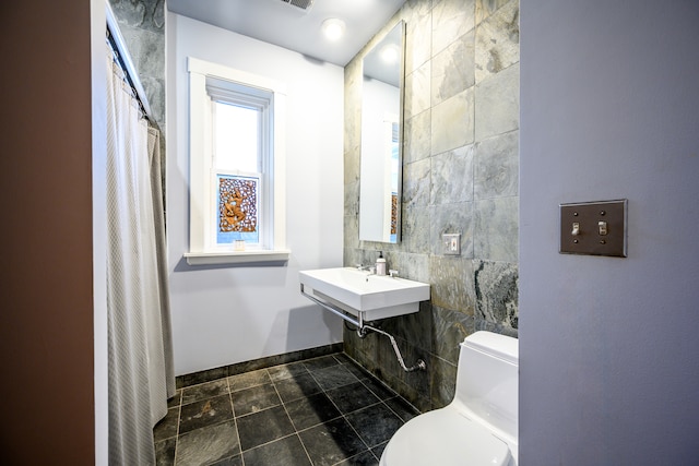 full bathroom featuring tile patterned flooring, toilet, a sink, tile walls, and baseboards