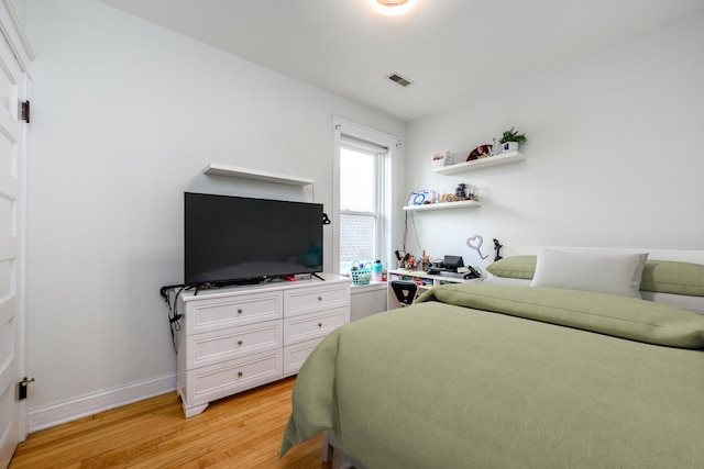 bedroom with light wood finished floors, baseboards, and visible vents
