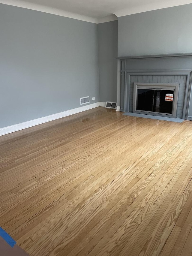 unfurnished living room with a fireplace, visible vents, and wood finished floors
