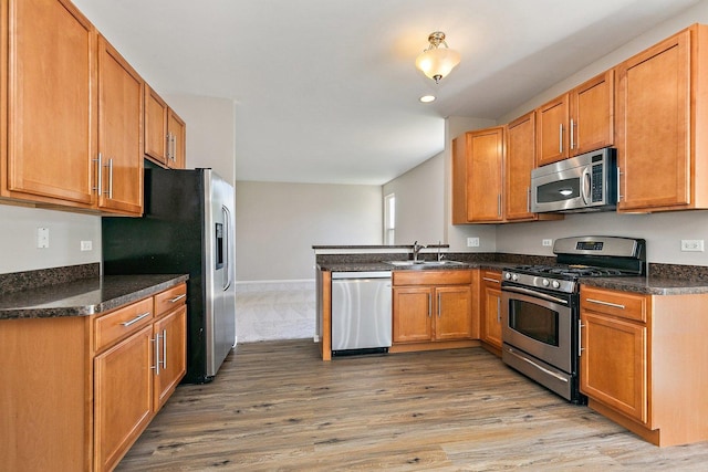 591 Waterford Rd, Elgin, IL 60124 - kitchen featuring stainless steel appliances, light wood finished floors, a peninsula, a sink, and brown cabinets