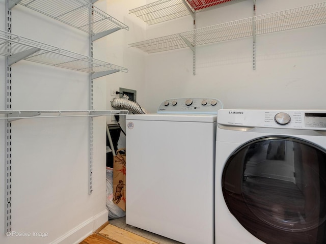 clothes washing area featuring light wood-type flooring, laundry area, and washing machine and clothes dryer