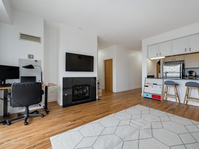 interior space with open floor plan, freestanding refrigerator, visible vents, and light wood-style flooring