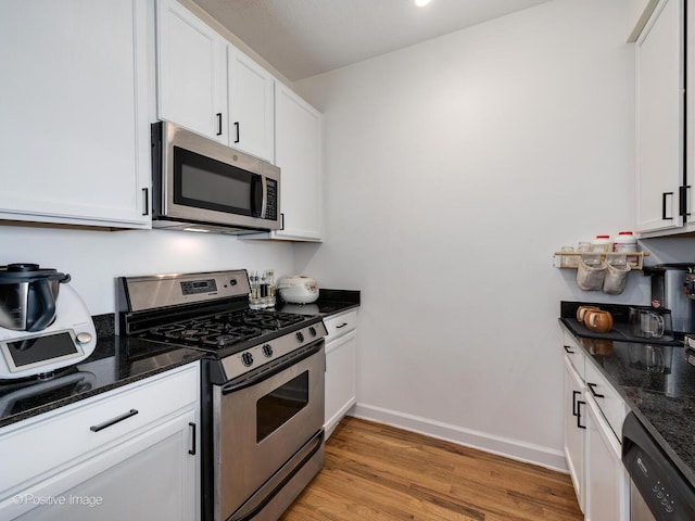kitchen featuring dark stone counters, white cabinets, and stainless steel appliances