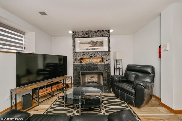 living room with wood finished floors, baseboards, a fireplace, and visible vents