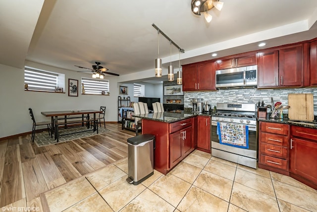 kitchen with decorative backsplash, a peninsula, stainless steel appliances, a ceiling fan, and reddish brown cabinets