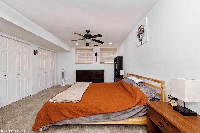 carpeted bedroom featuring two closets, recessed lighting, baseboards, and ceiling fan