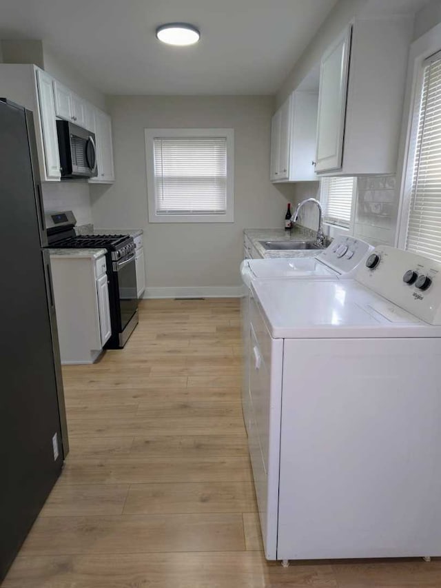 16117 Wolcott Ave, Markham, IL 60428 - laundry room with laundry area, light wood-style flooring, separate washer and dryer, a sink, and baseboards
