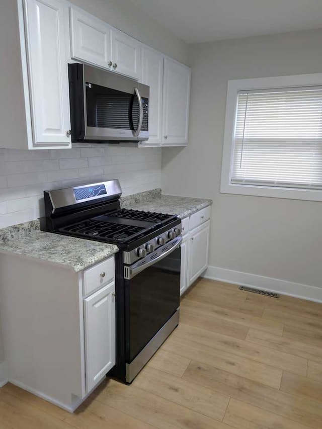 16117 Wolcott Ave, Markham, IL 60428 - kitchen with light wood-type flooring, white cabinetry, visible vents, decorative backsplash, and stainless steel appliances