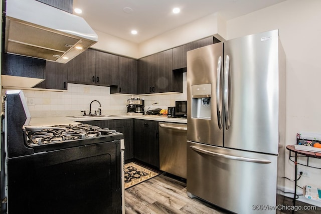 kitchen with light wood-style flooring, light countertops, under cabinet range hood, stainless steel appliances, and a sink