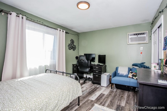 bedroom with wood finished floors and an AC wall unit